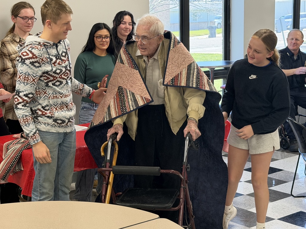 McCook Public Schools Students place the Quilt of Valor on their Great Grandpa John Hubert .
