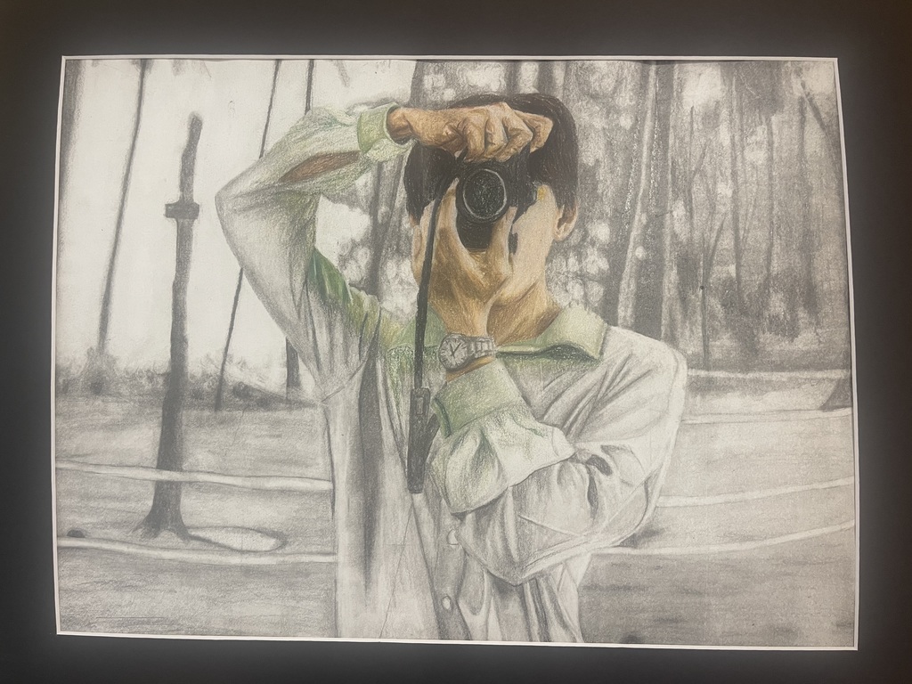 Self portrait of student taking a photo. The background is grayscale. The self-portrait incorporates a subtle amount of color, causes the focus of the photo to stand out.