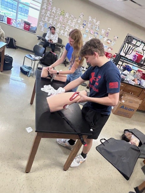 In these photos, students put their skills to the test during a Stop the Bleed tournament, competing to pack wounds and apply tourniquets quickly and effectively.