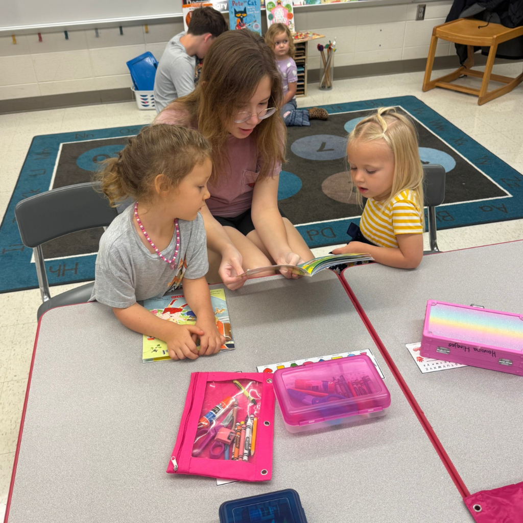 girl reading to two little girls