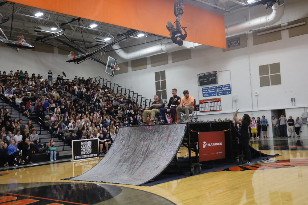 Photo of MCHS alum Matt Mecher performing a BMX stunt over MCHS principals