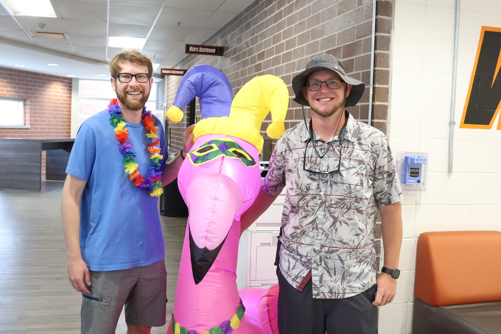 Mr. Stengel and Mr. Deener with an inflatable pink flamingo.  Mr. Stengel in a Hawaiin lei and Mr. Deener in a bucket hat, Hawaiian shirt and sunglasses on a necklace