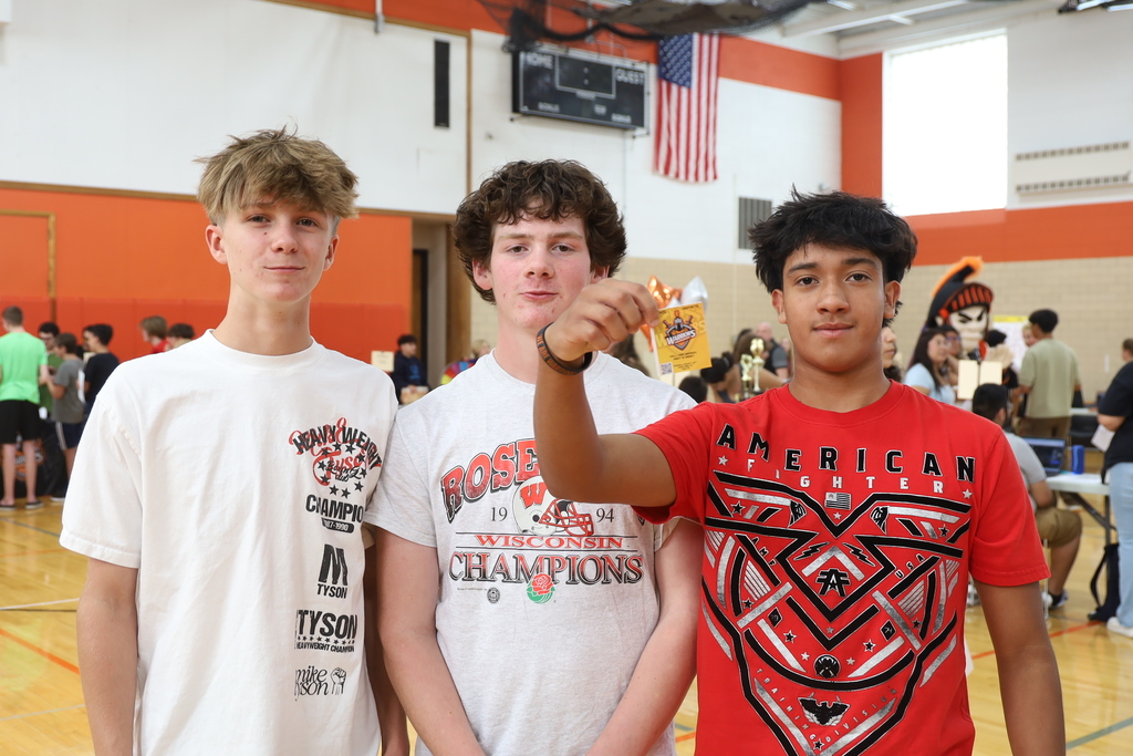 Three students one holding a sticker
