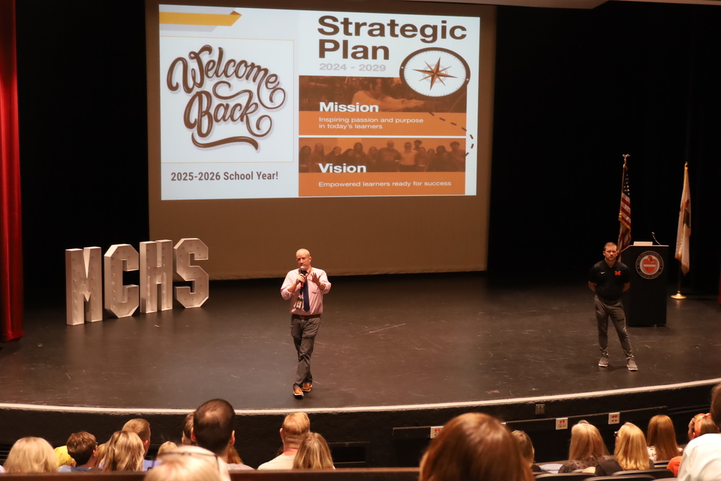 Principals on stage with Strategic Plan slide behind them and welcome back. 