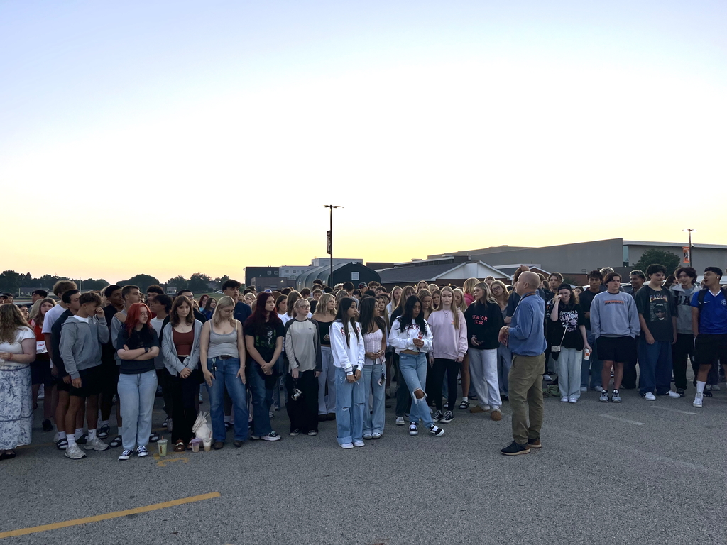 Students in the parking lot with principal and sunrise
