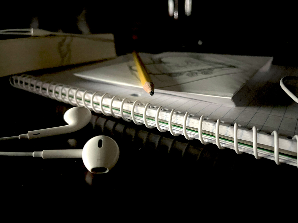 Ear buds next to a notebook with a pencil