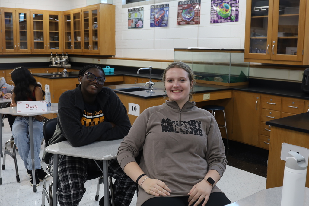 Two students in desks smiling at the camera