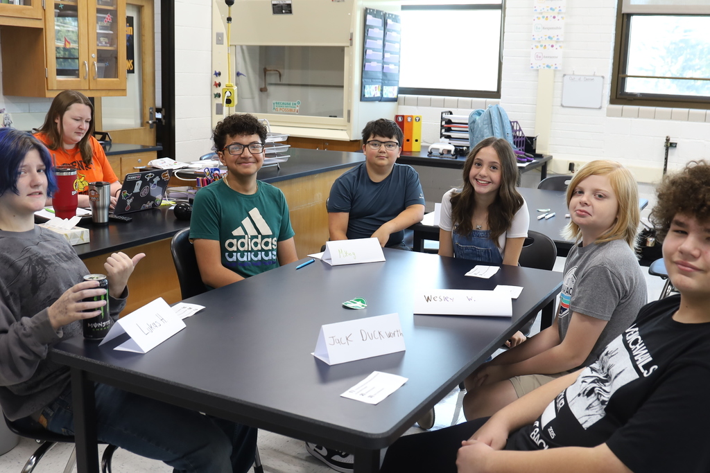 Six students at. table looking at the camera