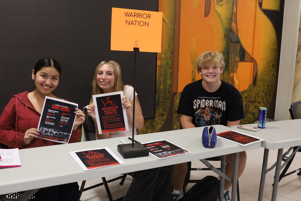 Three students at Warrior Nation booth holding flyers