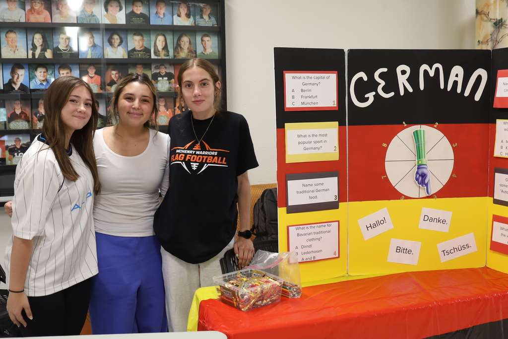 Three students next to German poster