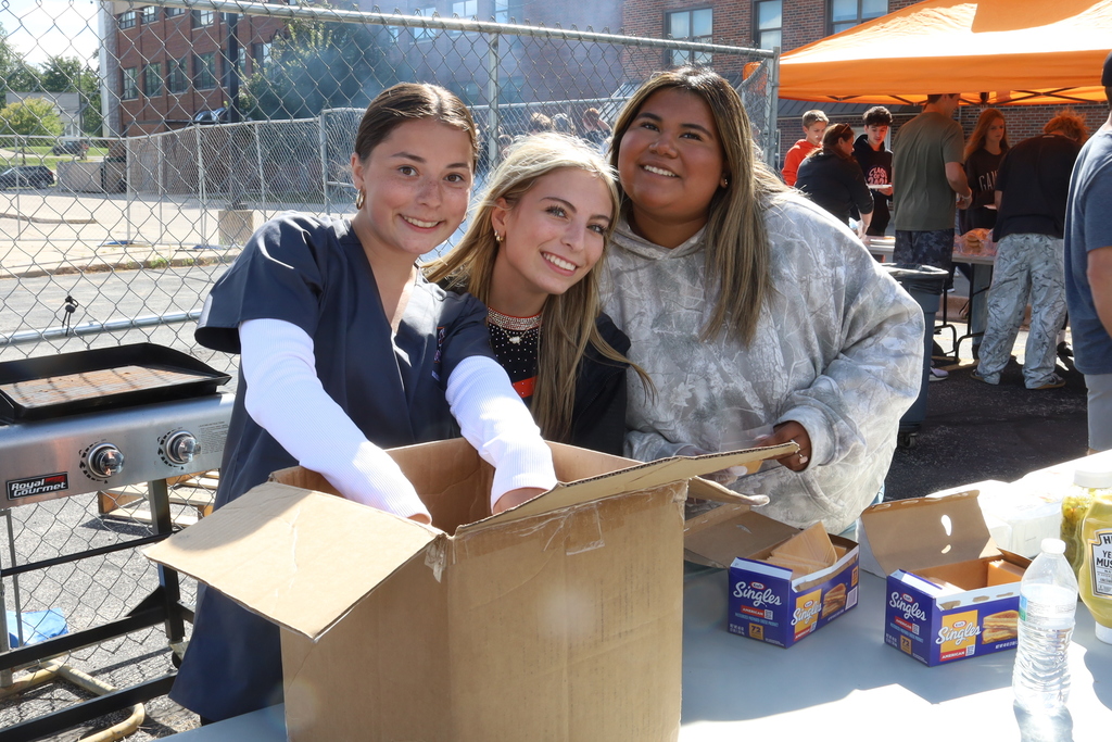 Three students helping with a box and smiling 