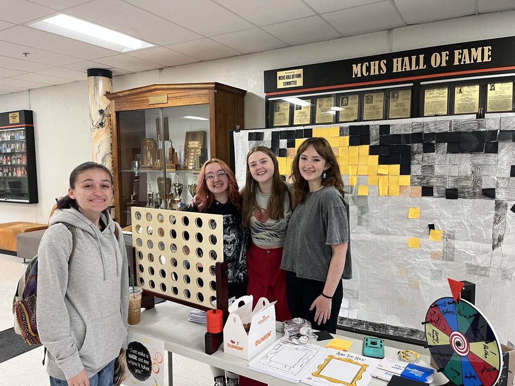 Students smiling, art work in the background, Connect Four, doughnut holes