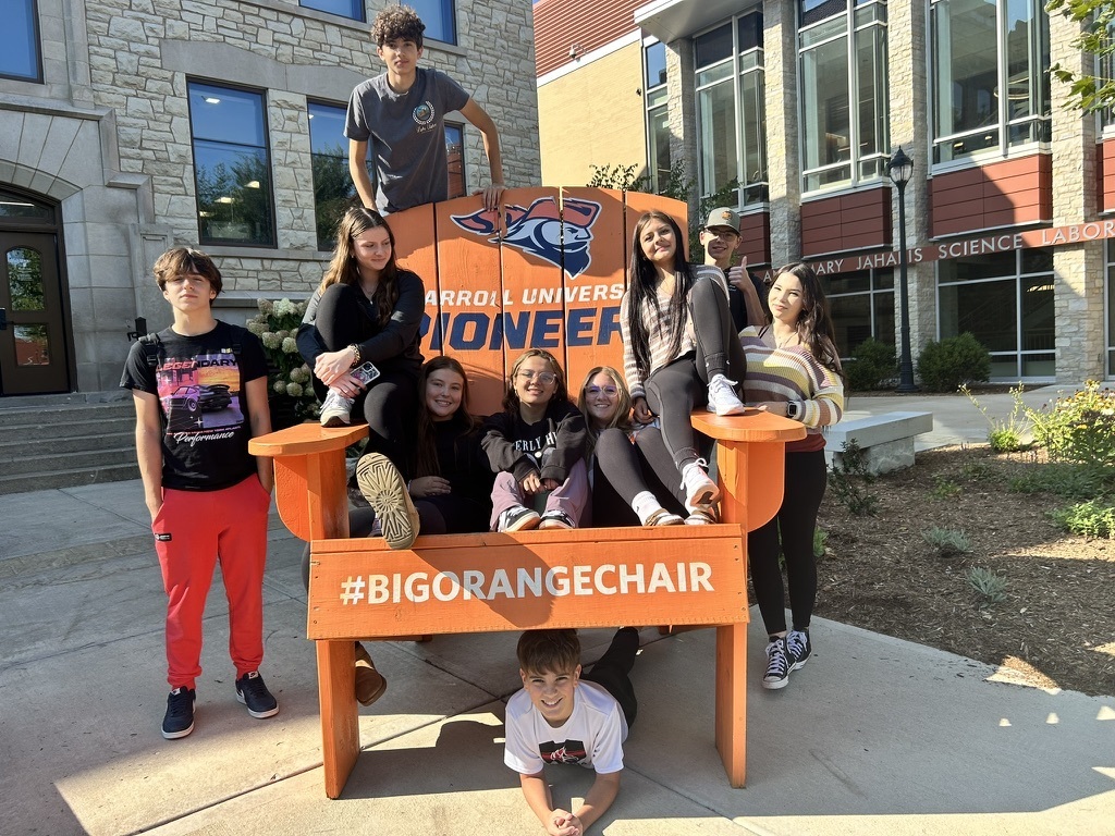 Students on a large Caroll University chair #BigOrangeChair
