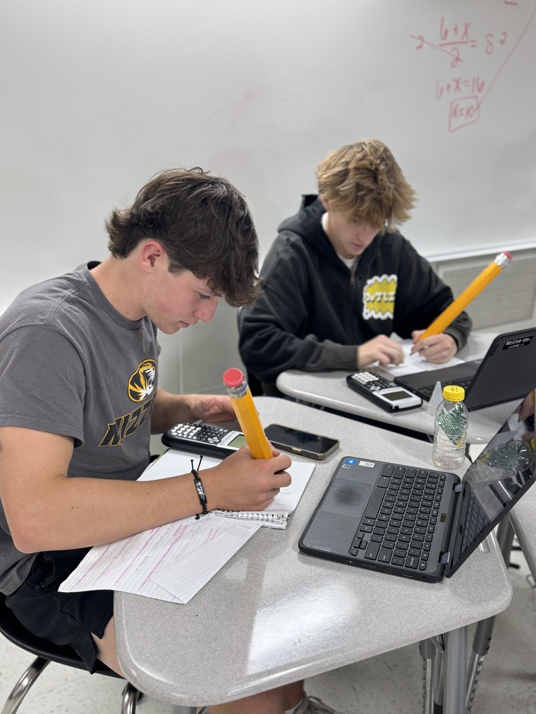 Photo of two Algebra II students using big pencils for class work