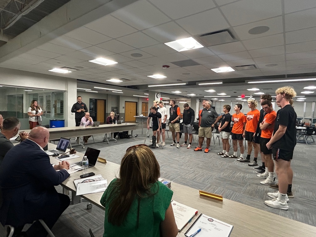 Baseball team standing in front of board of education meeting
