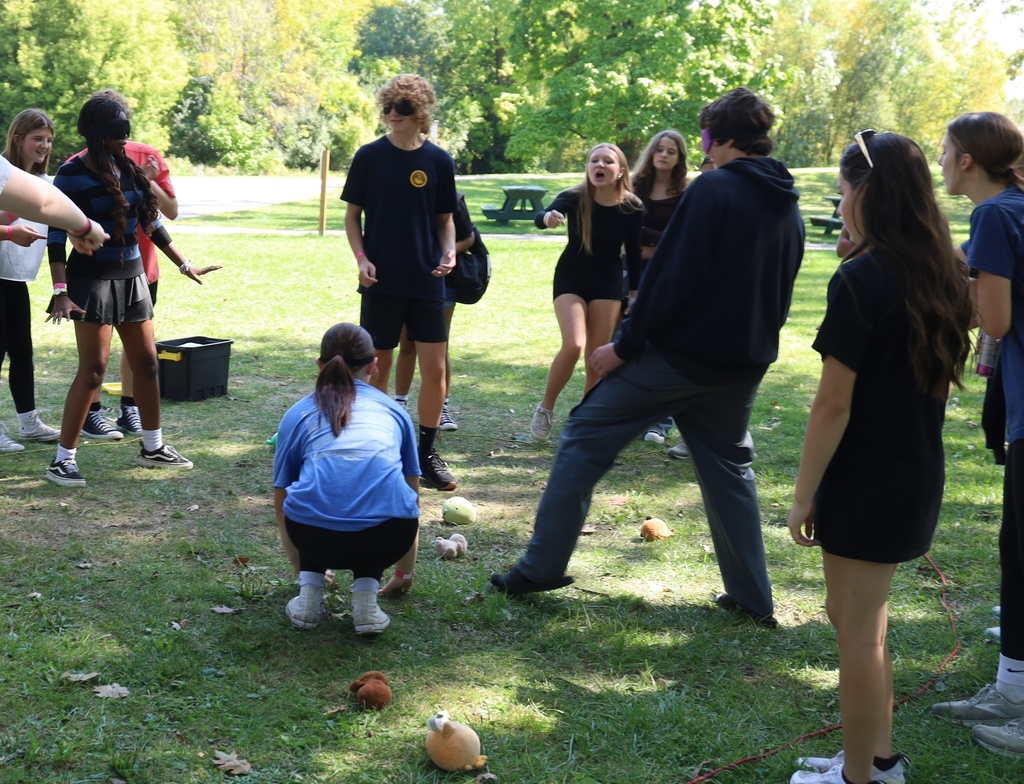Student on the ground, three students blind folded, another student pointing