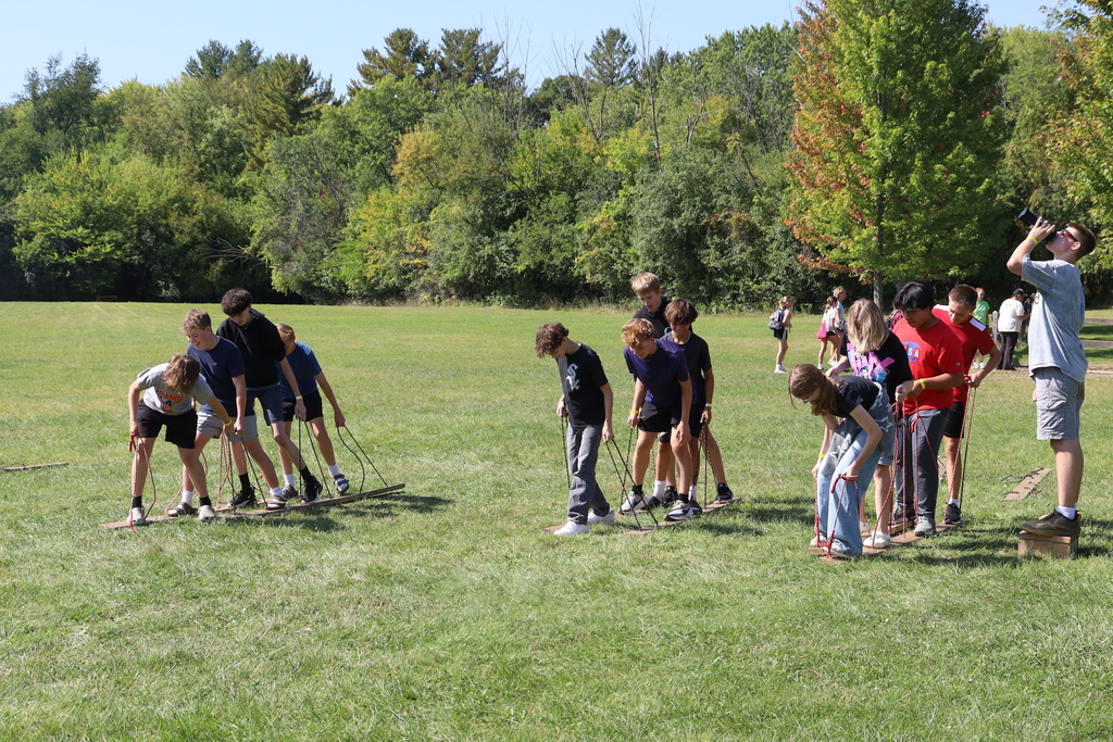 Students on ski-looking wooden boards held up by strings 