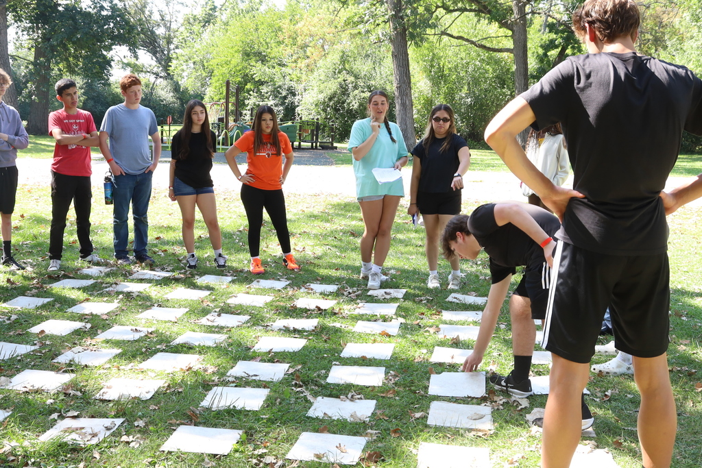Students standing around tiles, one picking a tile up 