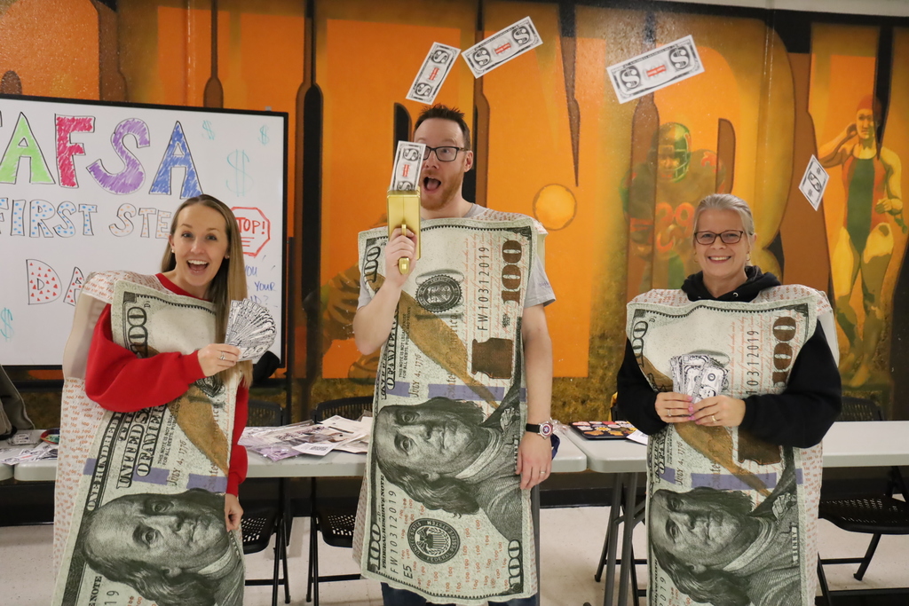Curtis Menke Amy Buchanan and Lauren Niemic in 100 dollar suits. Mr Menke shooting money out of a machine.