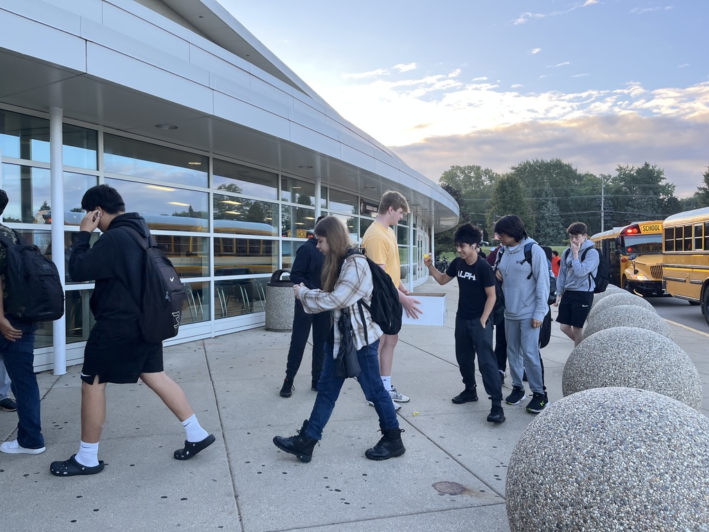 Students walking into the building. One holding a box of bracelets