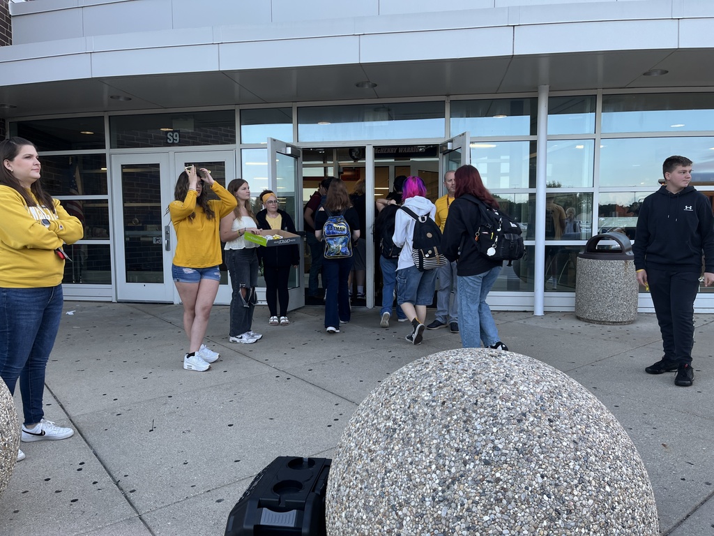Students walking into the building one student holding a box of bracelets