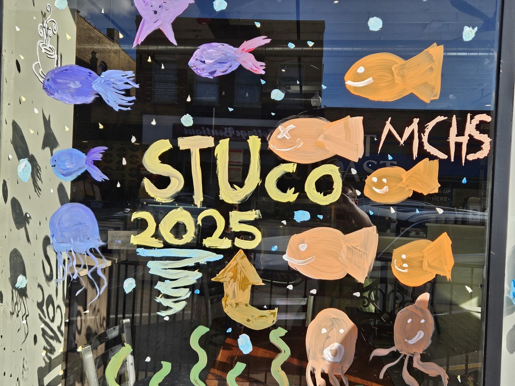 Photos of students painting storefront windows in downtown McHenry to celebrate the start of homecoming with a parade