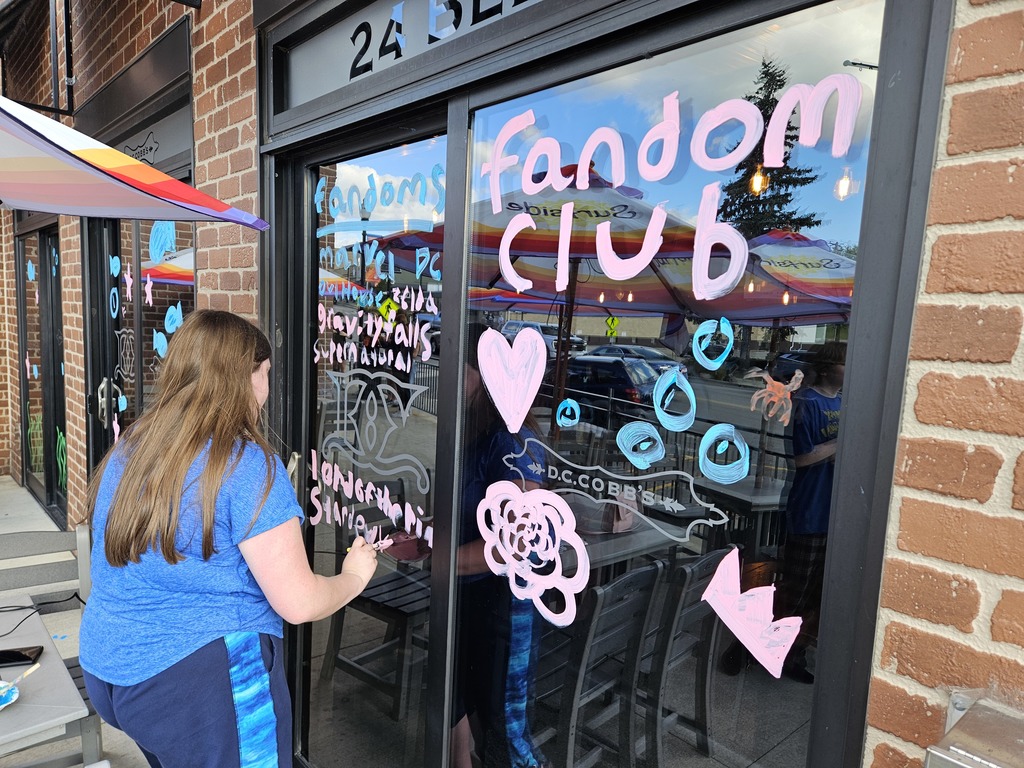 Photos of students painting storefront windows in downtown McHenry to celebrate the start of homecoming with a parade