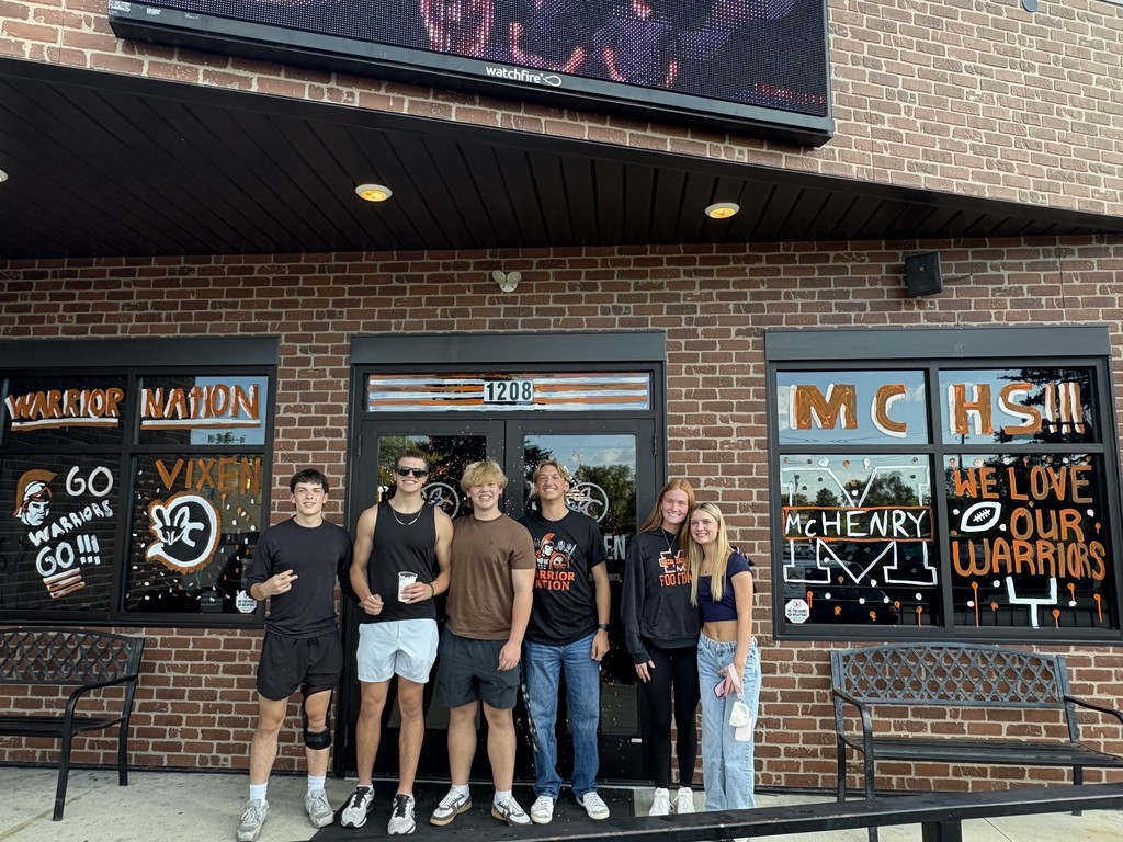 Photos of students painting storefront windows in downtown McHenry to celebrate the start of homecoming with a parade