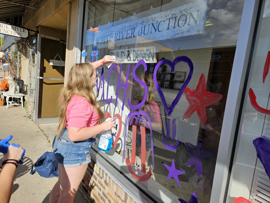 Photos of students painting storefront windows in downtown McHenry to celebrate the start of homecoming with a parade