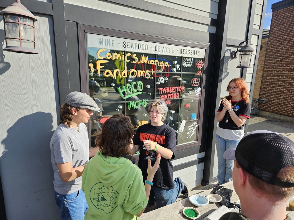 Photos of students painting storefront windows in downtown McHenry to celebrate the start of homecoming with a parade