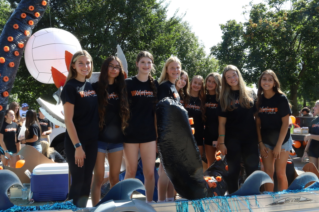 Volleyball students on a float decorated with a tentacle and a volleyball hanging behind it 