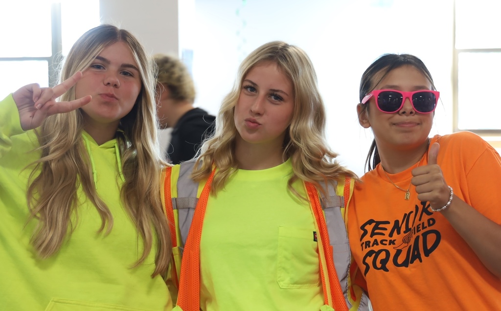 Two students in neon yellow, and one in neon orange