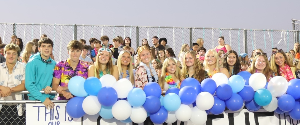 Students with blue and white balloons in student section with Hawaian gear