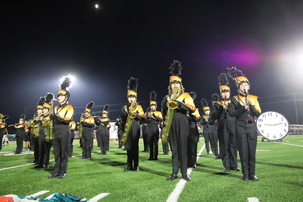 Marching band on the field with a giant clock