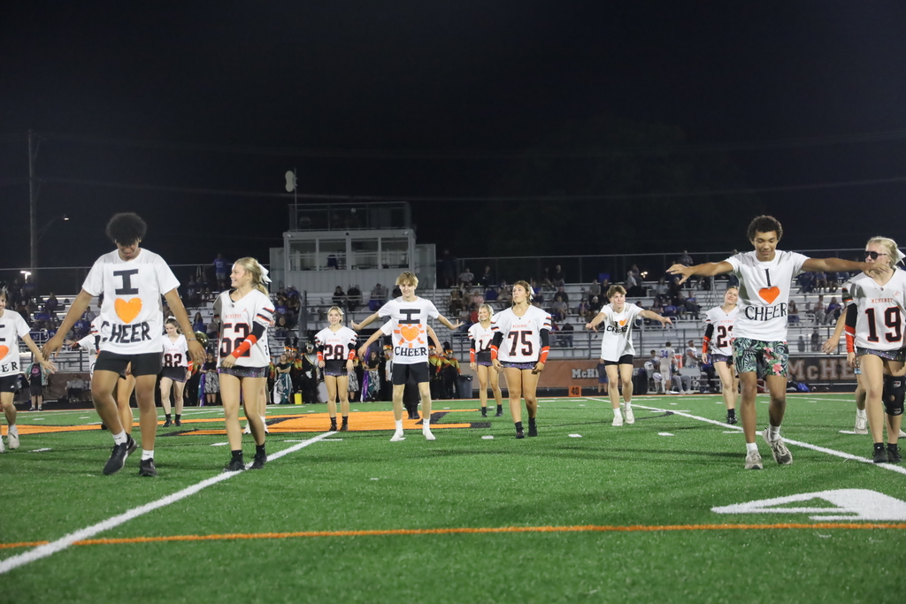 cheerleaders on field with partners wearing shirts that say "I love cheer."