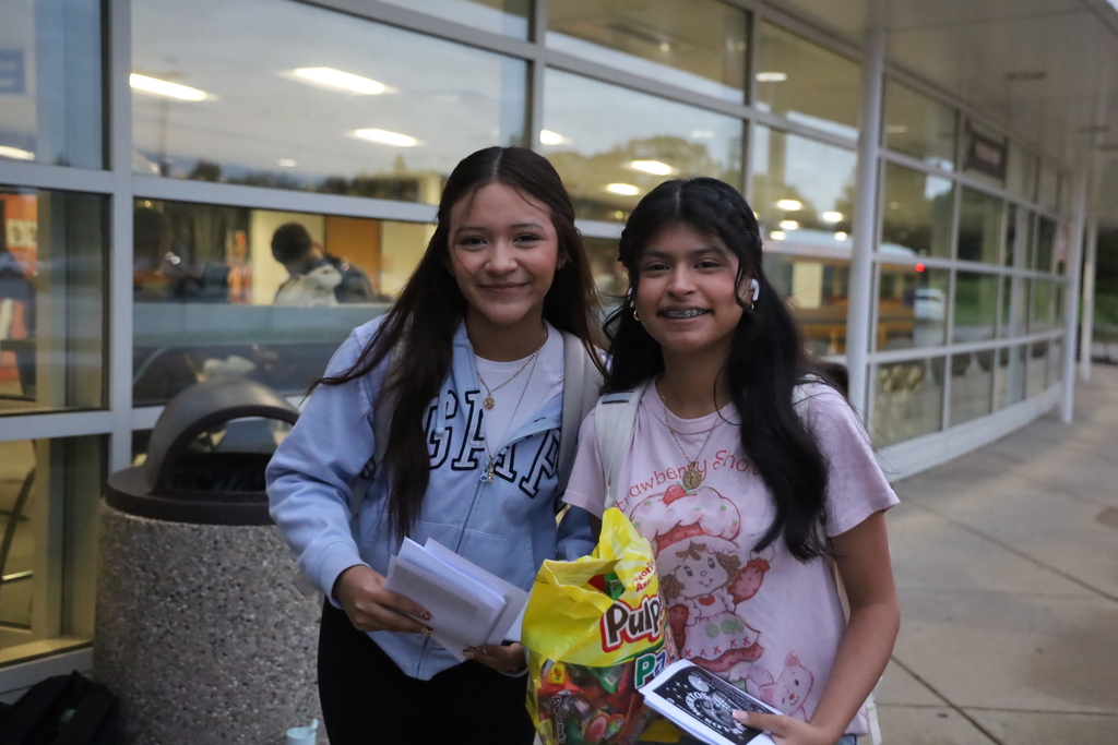 Two students smiling holding flyers and candy 