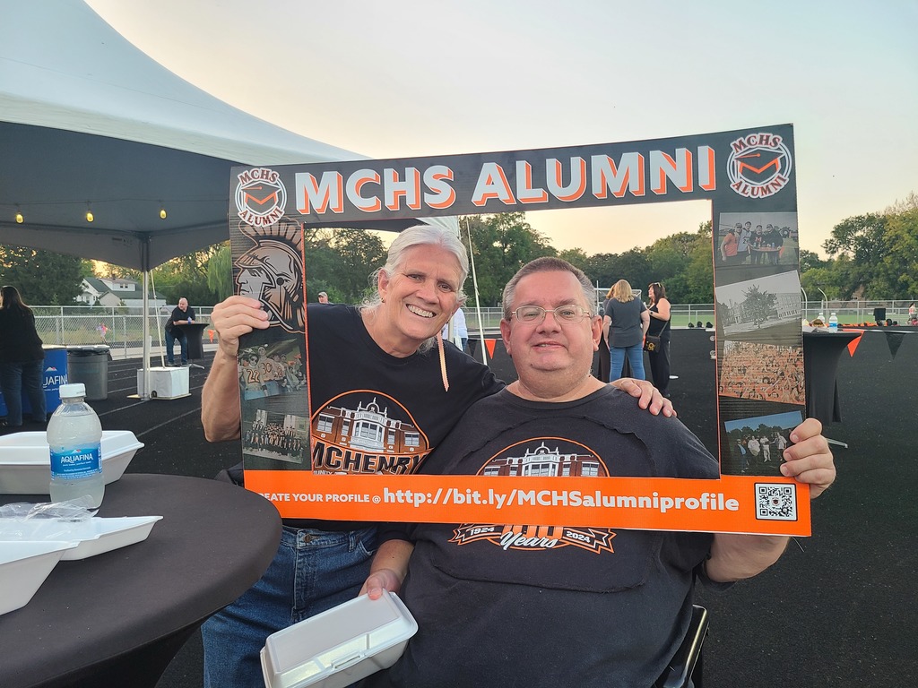 People posing in the alumni frame