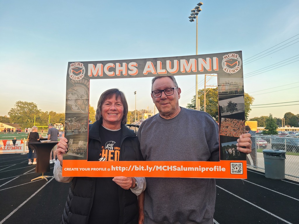 People posing in the alumni frame