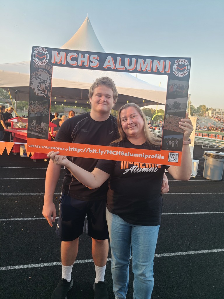 People posing in the alumni frame