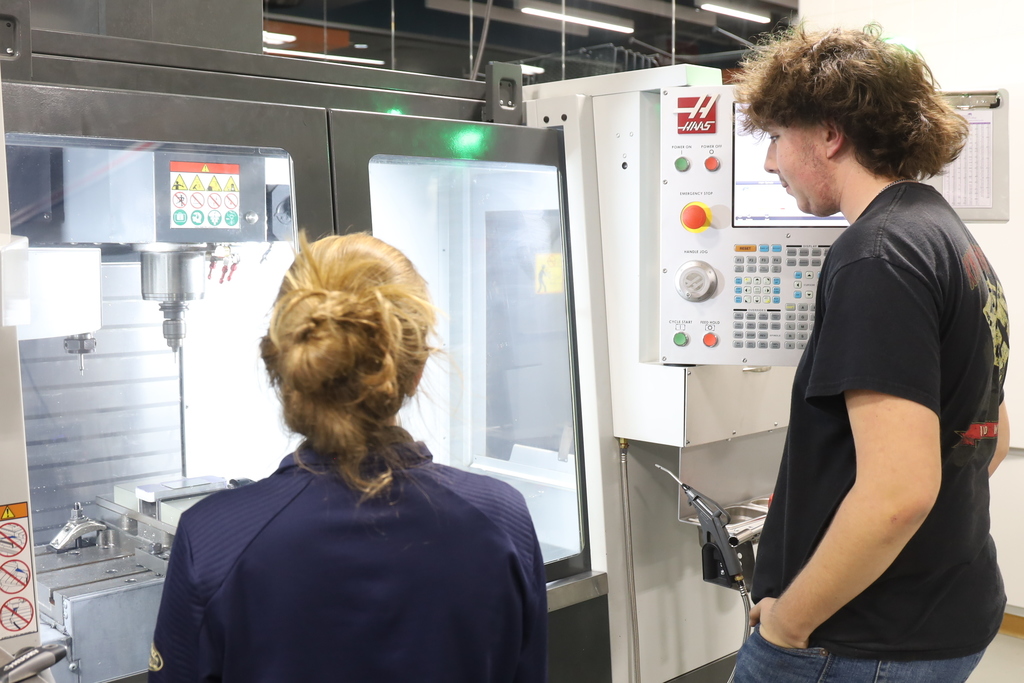 Two students looking at a manufacturing machine