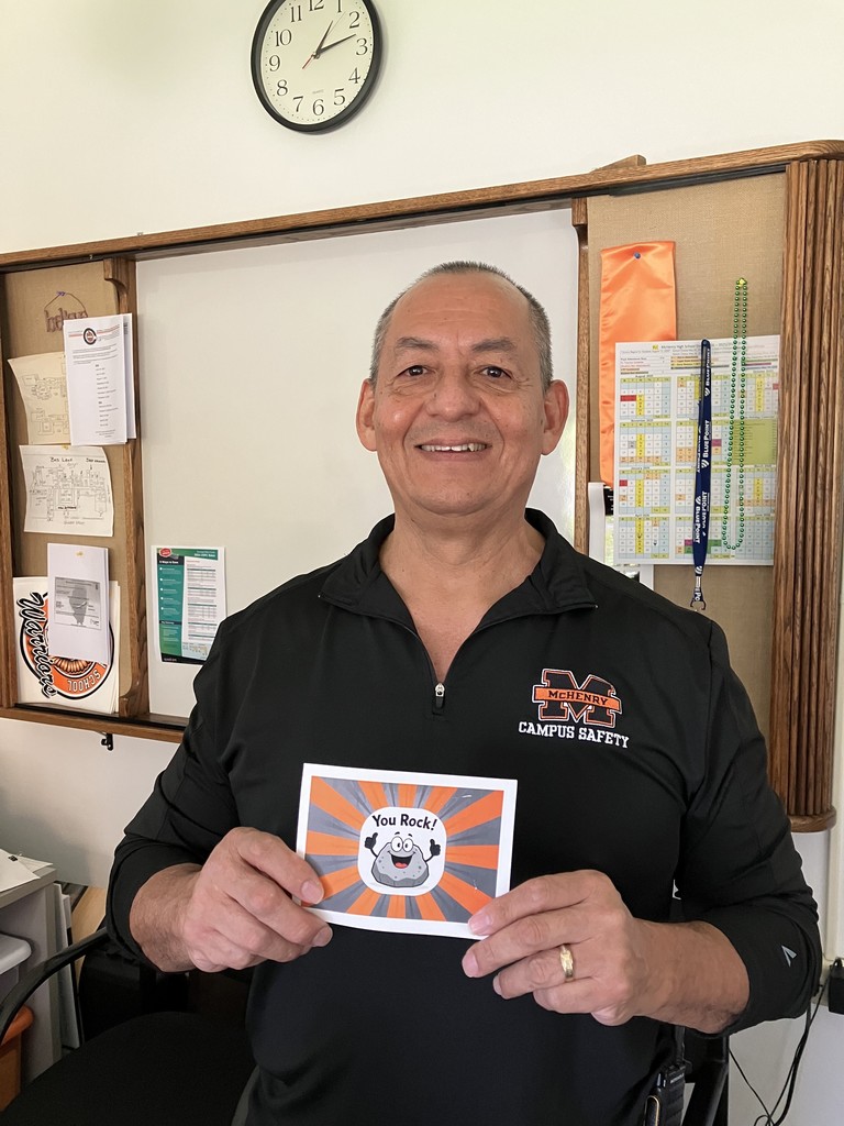 Alfredo Flores holding a postcard that says, "you rock"