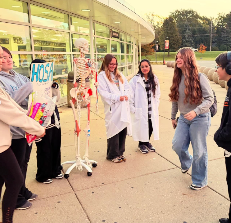 Students walking in near a HOSA Sign and candy with a skeleton display