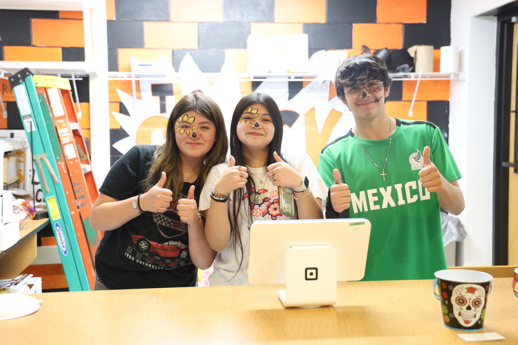 Three students with face paint with their thumbs up where you at the concessions