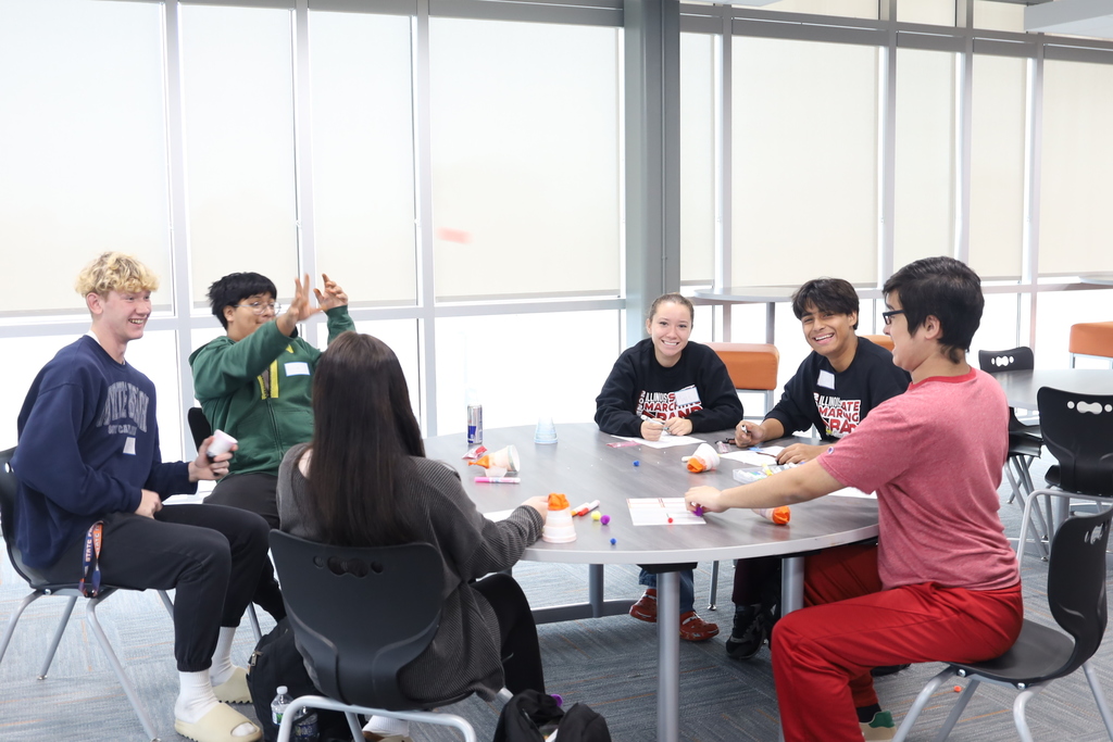 Students at a table with activities , one throwing something 