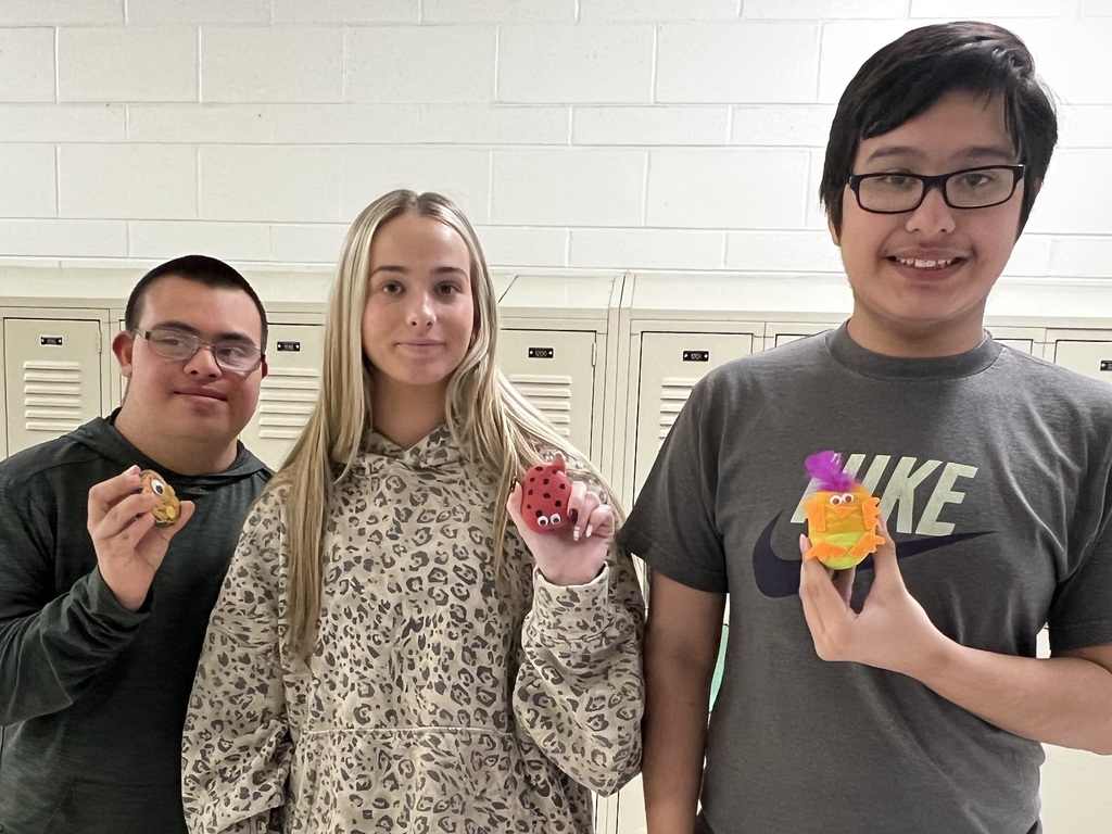 Students holding pet rocks they designed