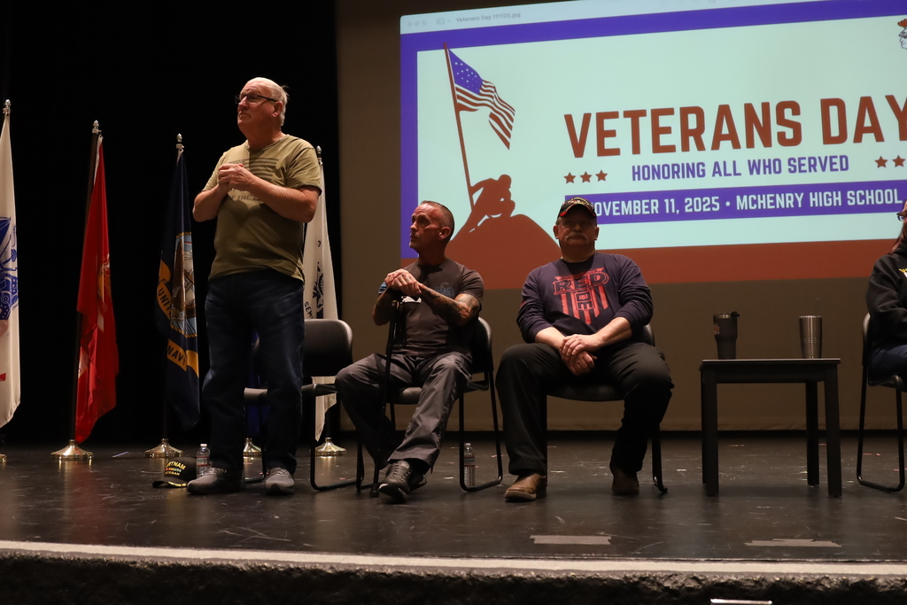 Veterans on stage with Veterans Day background