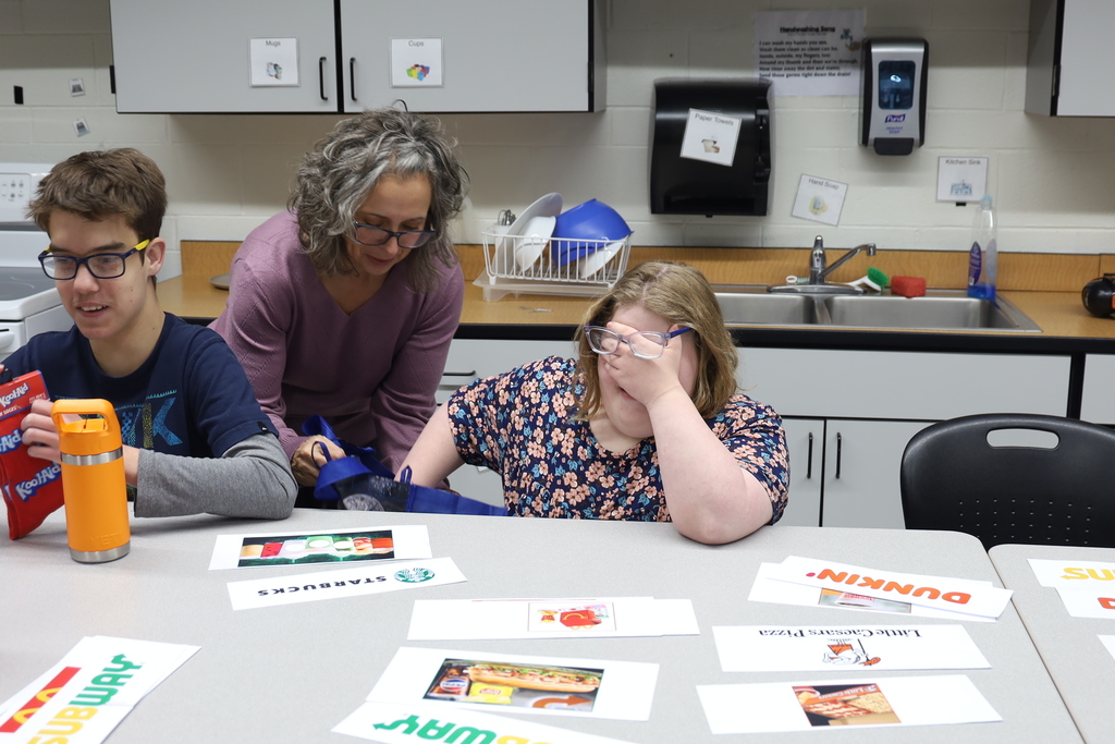 Student with eyes closed getting something out of teacher's bag
