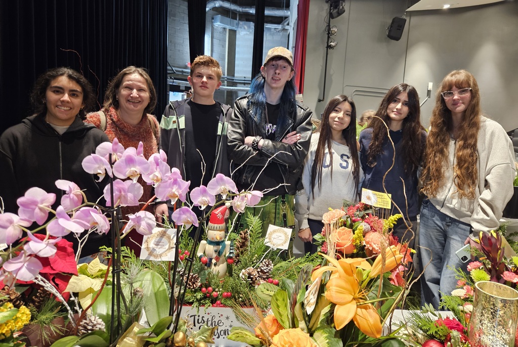 Students and advisor standing by flowers