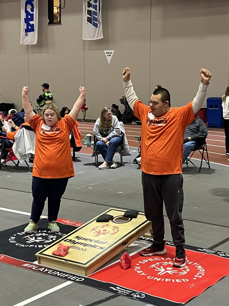 Two students putting their hands in the air at cornhole Special Olympics tournament