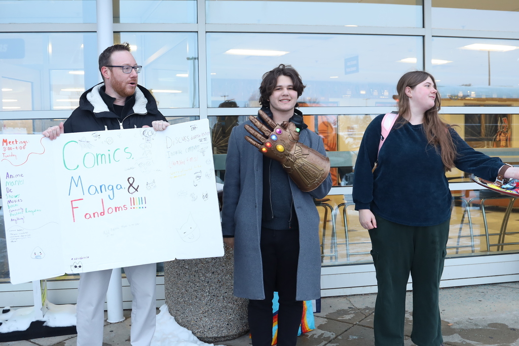 Advisor with Comics Manga and Fandoms psoter, student with Thanos hand and other student handing out candy.